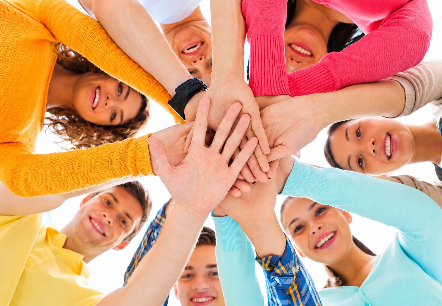 Groupe de jeunes souriants, mains empilées