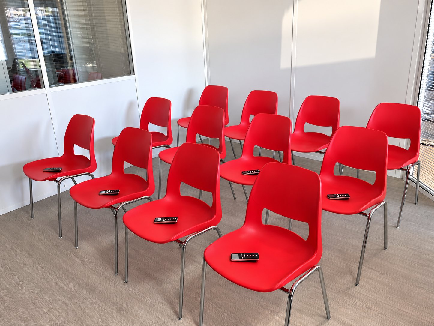 Salle de code avec chaises rouges et télécommandes de vote
